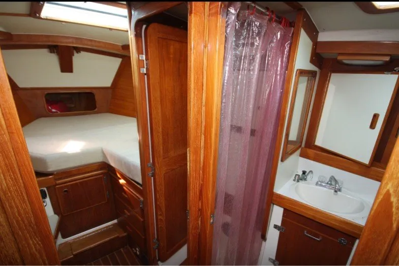 Slide: The Image of 1988 Sceptre 41 yacht interior with wooden cabinetry, bed, and compact bathroom. - 15