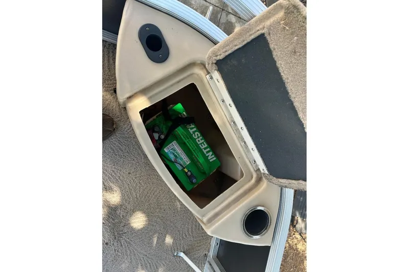 Slide: The Image of Open storage compartment on 2011 Bennington 24 SFi boat with visible green battery. - 7