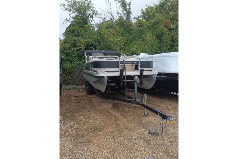 The Image of 2011 Bennington 24 SFi pontoon boat on trailer, parked outdoors with greenery background. - 0
