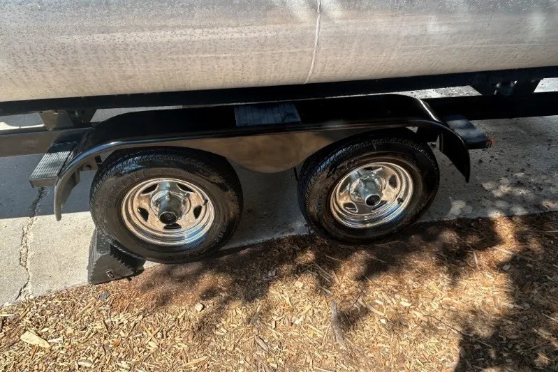 Slide: The Image of Trailer wheels of a 2011 Bennington 24 SFi boat, parked on a driveway. - 9