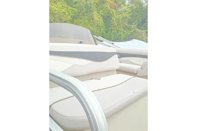 Slide: The Image of 2011 Bennington 24 SFi boat interior with beige seating and lush greenery background. - 15