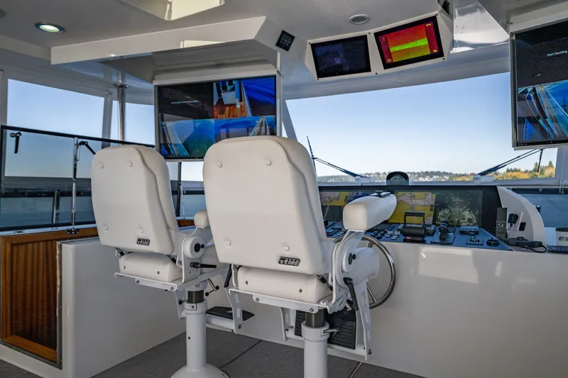 Slide: The Image of Cockpit of 2012 Ocean Alexander 85 E yacht with dual white captain chairs and navigation screens. - 77