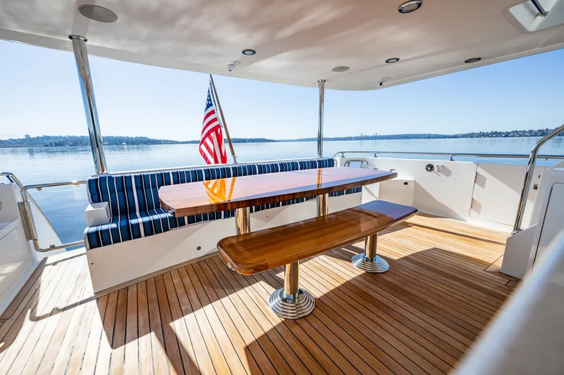 Slide: The Image of Luxurious Ocean Alexander 85 E yacht deck with wooden table, striped seating, and scenic water view. - 81