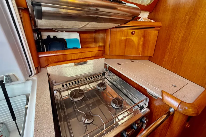 Slide: The Image of Galley kitchen in 2007 Jeanneau Sun Odyssey 49 DS sailboat with stove and wooden cabinetry. - 61