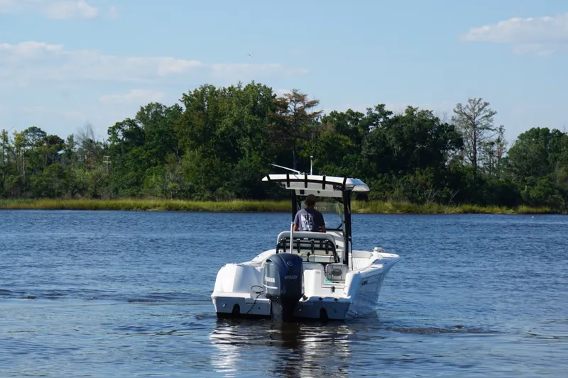 Slide: The Image of 2021 Sea Fox 248 Commander boat cruising on a serene lake with lush green shoreline. - 3