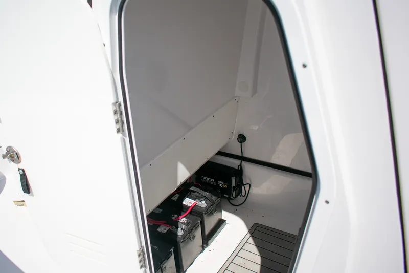 Slide: The Image of 2023 Sportsman Masters 247 Bay Boat storage compartment with batteries and charger. - 17