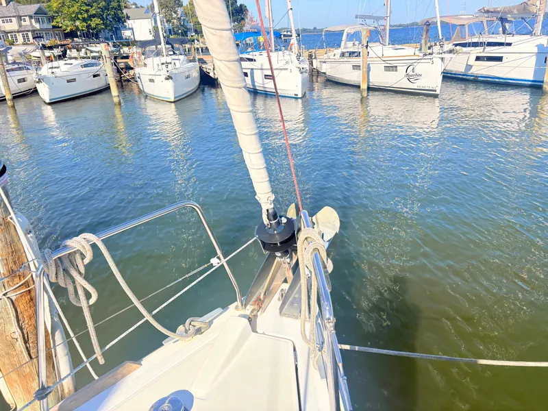 Slide: The Image of A sailboat is docked in a marina, surrounded by other boats. The water is calm and clear. - 12