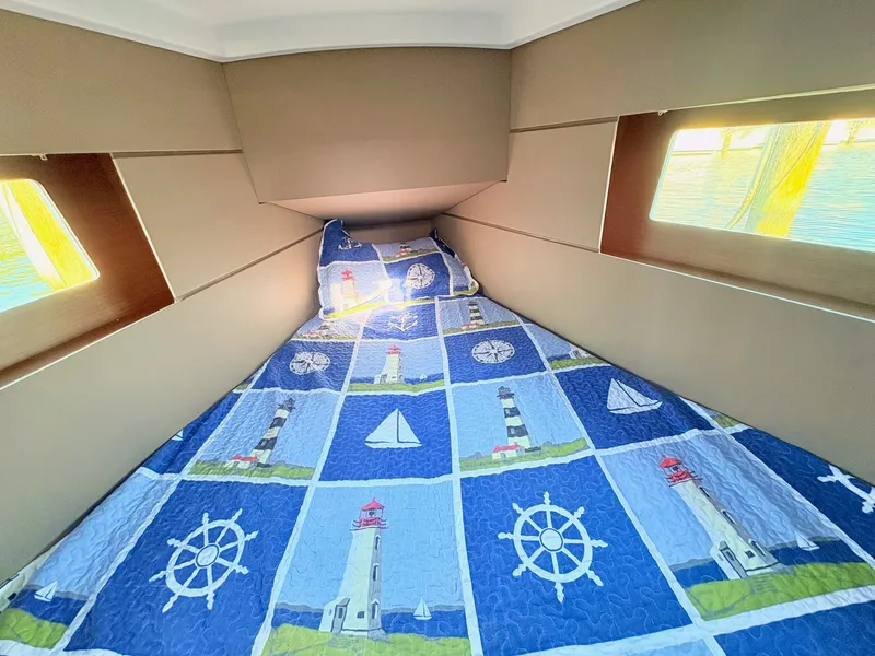 Slide: The Image of The cabin of the 2020 Beneteau Oceanis 35.1 features a cozy bed with nautical-themed bedding. - 28