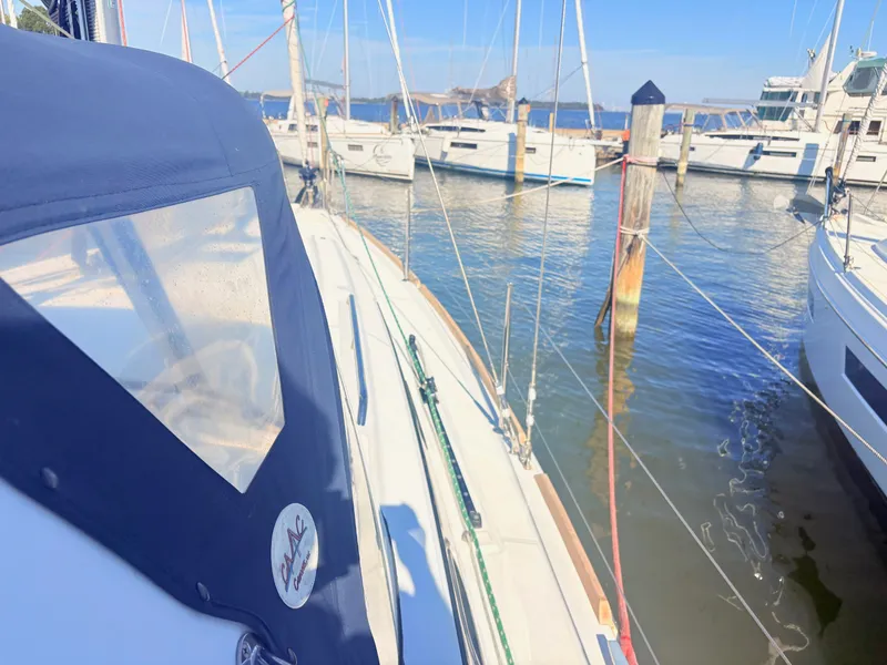 Slide: The Image of A sailboat is docked in a calm marina. It features a blue canopy and is surrounded by other boats. - 9