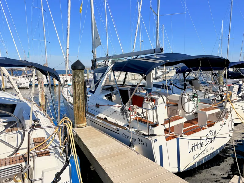 Slide: The Image of A 2020 Beneteau Oceanis 35.1 sailboat docked, featuring a blue sunshade and sleek design. - 44