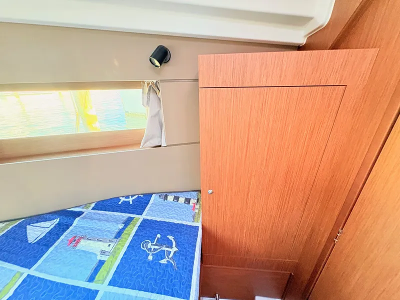 Slide: The Image of Interior of a 2020 Beneteau Oceanis 35.1 with wooden furnishings and a bed with nautical-themed bedding. - 27