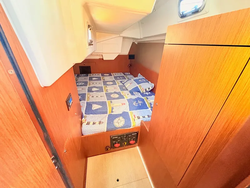 Slide: The Image of The cabin of the 2020 Beneteau Oceanis 35.1 features a cozy bed with nautical-themed bedding. - 36