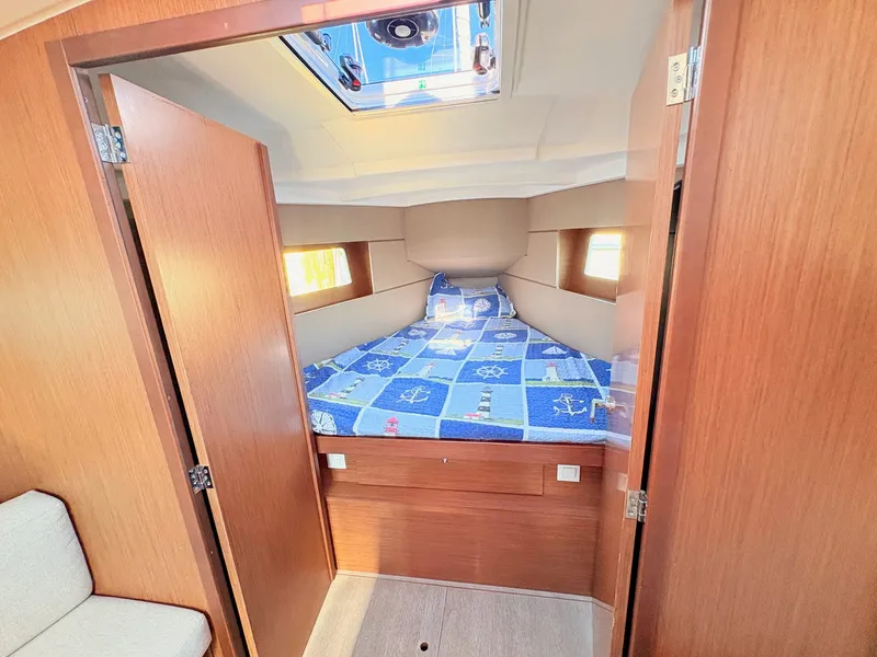 Slide: The Image of The cabin of a 2020 Beneteau Oceanis 35.1 with a cozy bed and wooden doors. - 26