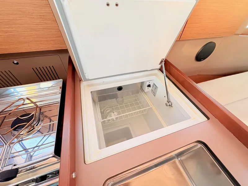 Slide: The Image of The 2020 Beneteau Oceanis 35.1 galley features an open fridge and a stainless steel sink. - 35