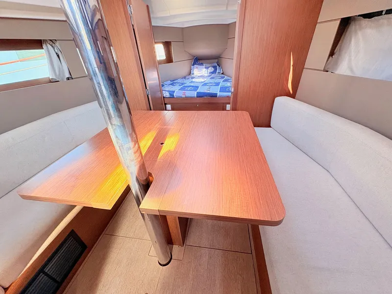 Slide: The Image of Interior of a Beneteau Oceanis 35.1 with a wooden table, beige sofas, and a bed in the background. - 25