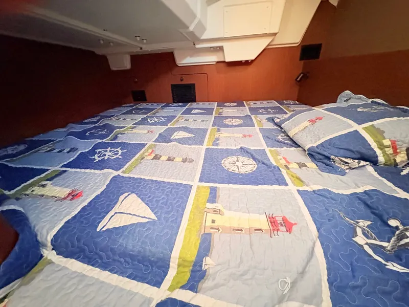 Slide: The Image of The cabin of a 2020 Beneteau Oceanis 35.1 with a nautical-themed bedspread. - 38