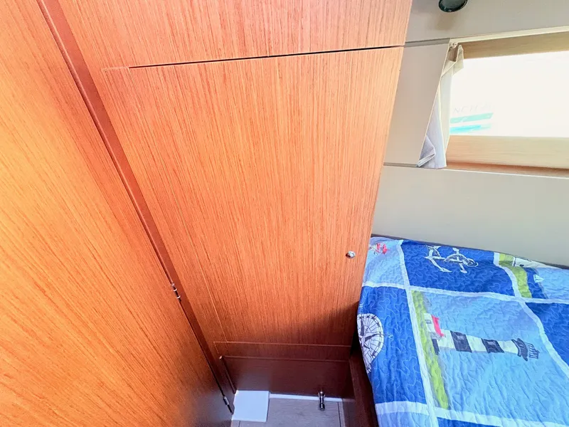 Slide: The Image of The cabin of a 2020 Beneteau Oceanis 35.1 with wooden walls and a bed with nautical-themed bedding. - 29