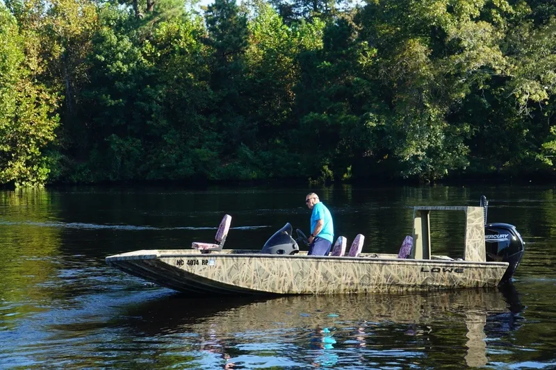Slide: The Image of Man on a 2025 Lowe Outlet 20 boat in a scenic river setting. - 1