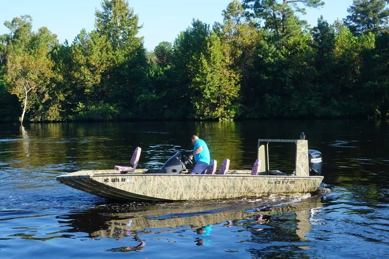 Slide: The Image of Man operating 2025 Lowe Outlet 20 boat on a serene river. - 2