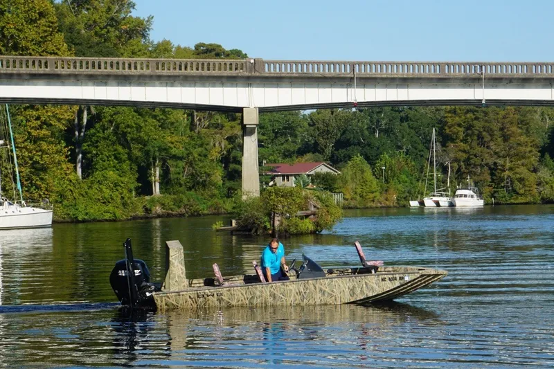 Slide: The Image of A Lowe Outlet 20 boat on a scenic river under a bridge, 2025 model. - 5