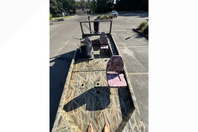 Slide: The Image of 2025 Lowe Outlet 20 boat with camouflage design, parked in an empty lot. - 16