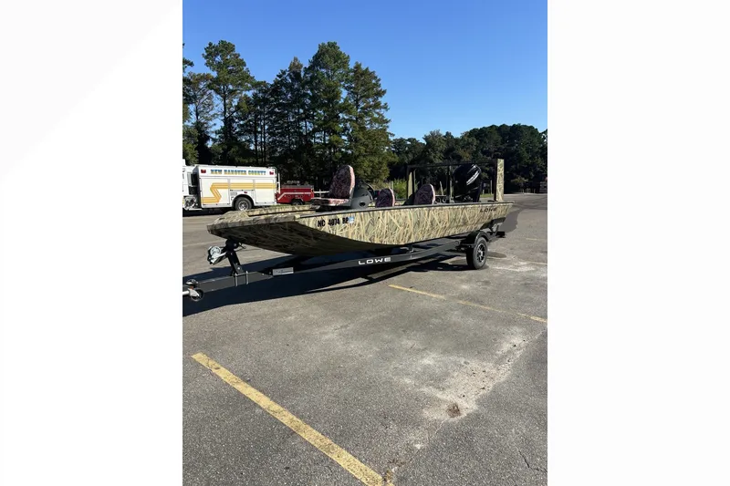 Slide: The Image of 2025 Lowe Outlet 20 boat with camouflage design on a trailer in a parking lot. - 9