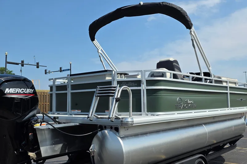 The Image of 2027 Sun Tracker Fishin' Barge 20 DLX pontoon boat with Mercury engine, docked outdoors. - 0