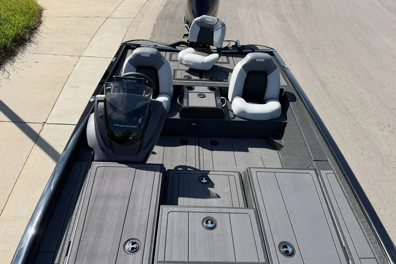 Slide: The Image of 2027 Tracker Savage 215 boat interior with seating and Garmin console, parked on pavement. - 23