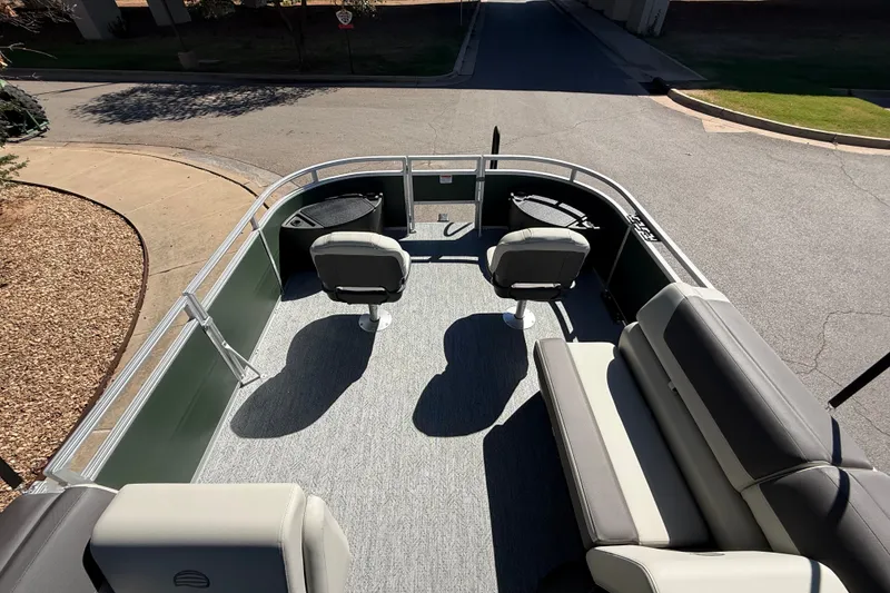 Slide: The Image of 2027 Sun Tracker Fishin' Barge 22 DLX interior with seating and helm, parked on pavement. - 15