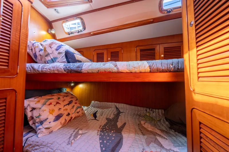 Slide: The Image of Cozy cabin interior of 2004 Hylas 54 yacht with wooden bunk beds and nautical-themed bedding. - 21