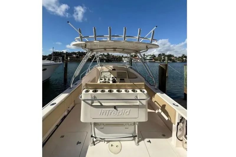 Slide: The Image of 2008 Intrepid 370 Cuddy boat docked, featuring spacious deck and fishing rod holders. - 18