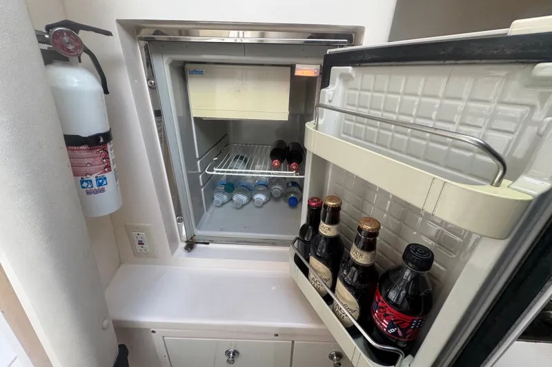 Slide: The Image of Mini fridge on 2008 Intrepid 370 Cuddy boat, stocked with drinks and a fire extinguisher nearby. - 58