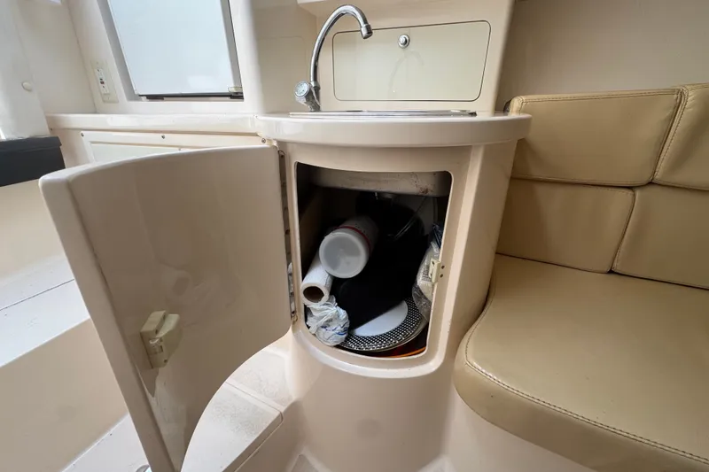 Slide: The Image of 2008 Intrepid 370 Cuddy interior with open cabinet, sink, and beige seating. - 54