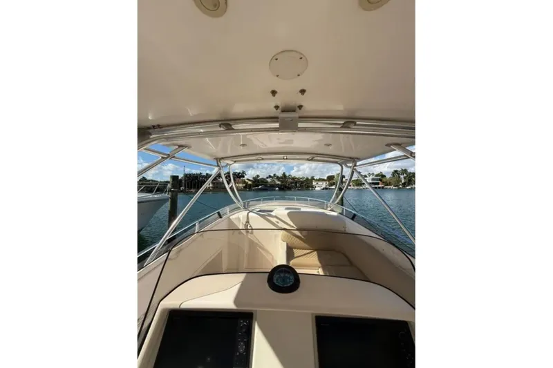 Slide: The Image of 2008 Intrepid 370 Cuddy boat interior with helm view, overlooking calm waters and shoreline. - 26