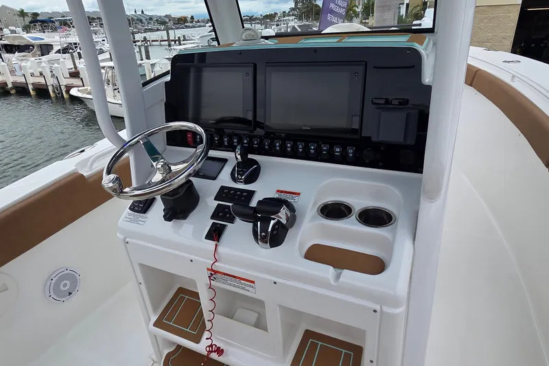Slide: The Image of 2021 Sea Hunt Gamefish 27CB helm with dual displays and steering wheel at marina. - 18
