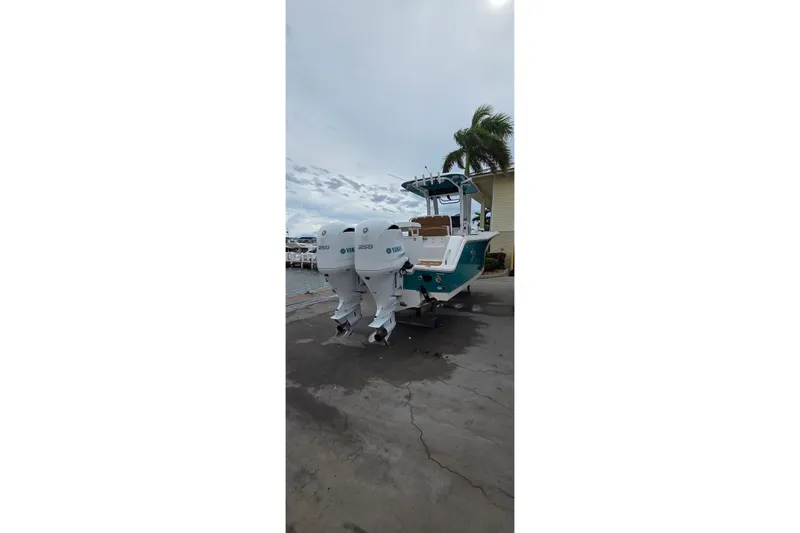Slide: The Image of 2021 Sea Hunt Gamefish 27CB boat with twin Yamaha engines docked near palm trees. - 28