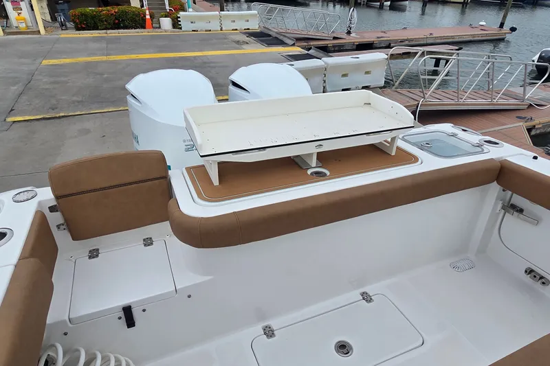 Slide: The Image of 2021 Sea Hunt Gamefish 27CB boat interior with seating and storage at dock. - 13