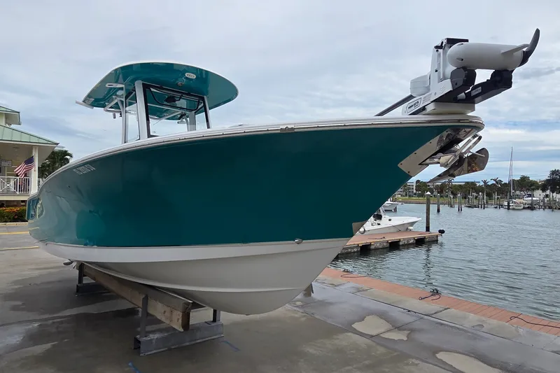 The Image of 2021 Sea Hunt Gamefish 27CB boat docked at marina, featuring sleek design and teal hull. - 0