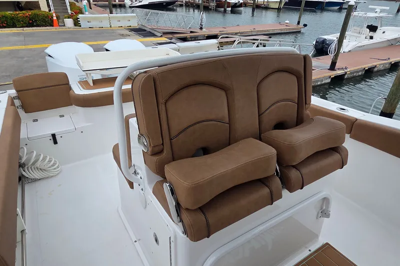 Slide: The Image of 2021 Sea Hunt Gamefish 27CB boat with brown cushioned seating at a marina dock. - 14