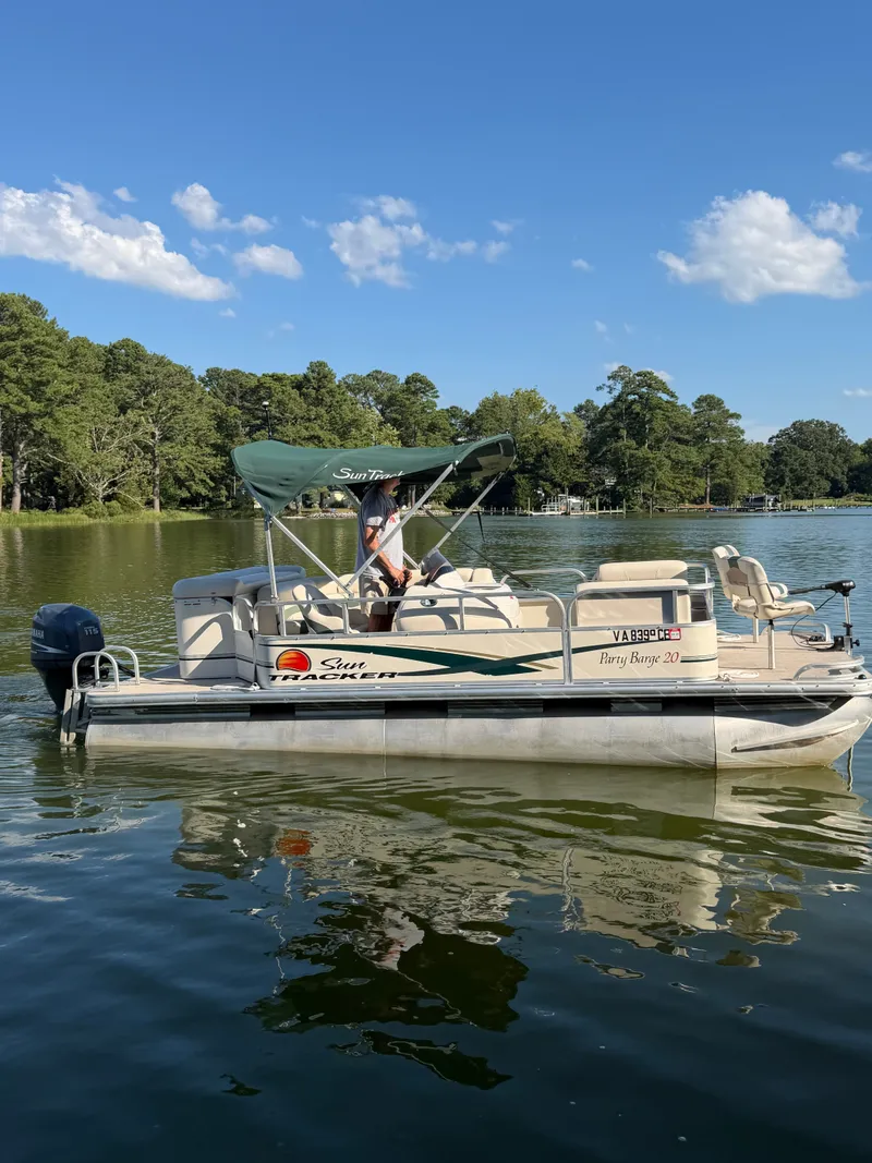 The Image of A 2011 Sun Tracker Party Barge 20 Classic Series floats on a calm lake. - 0