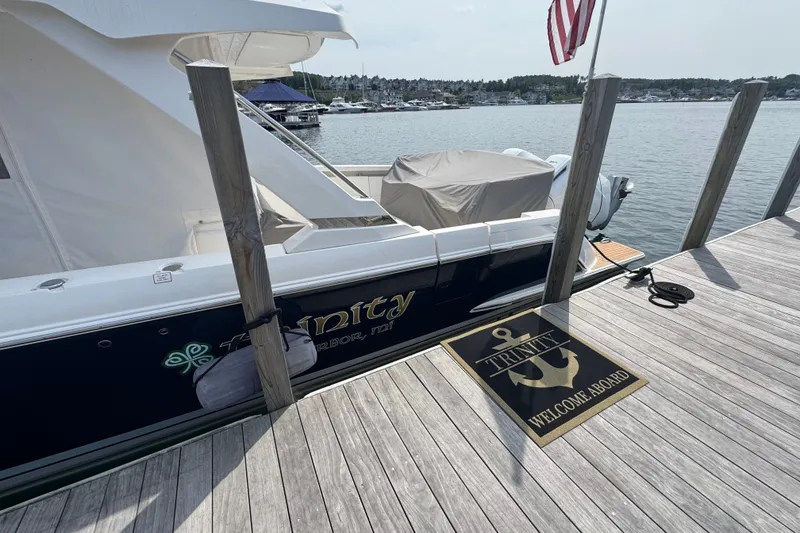 Slide: The Image of 2022 Tiara Yachts 43 LS docked, featuring "Trinity" welcome mat and American flag. - 27