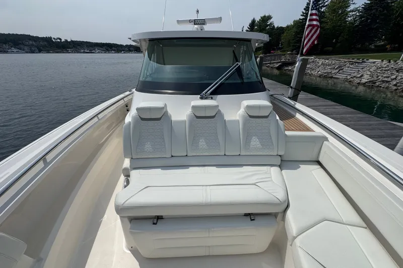 Slide: The Image of 2022 Tiara Yachts 43 LS luxury boat with white seating, docked by a scenic shoreline. - 11