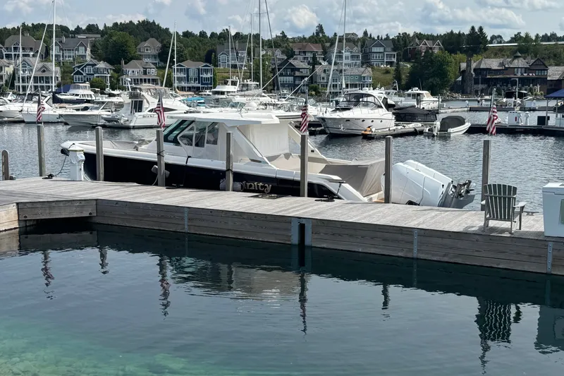 Slide: The Image of 2022 Tiara Yachts 43 LS docked at a marina with scenic waterfront homes. - 28