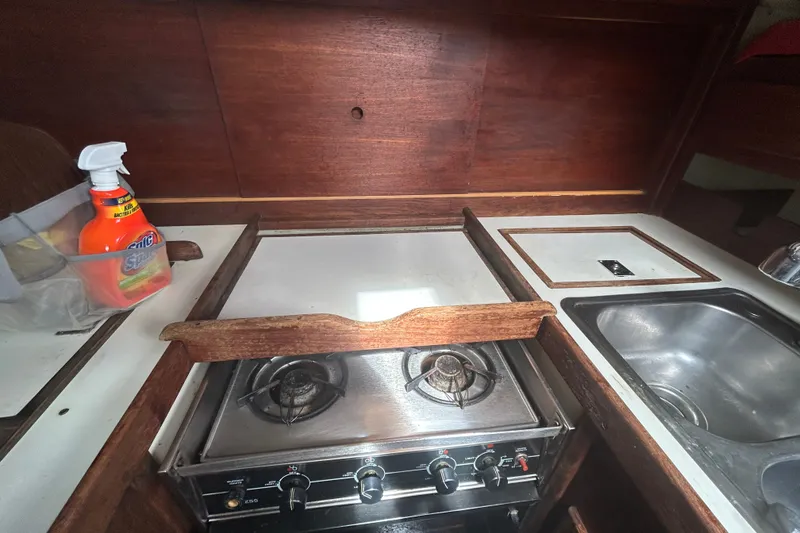 Slide: The Image of 1979 Tartan 37 yacht kitchen with stove, sink, and cleaning supplies. - 34
