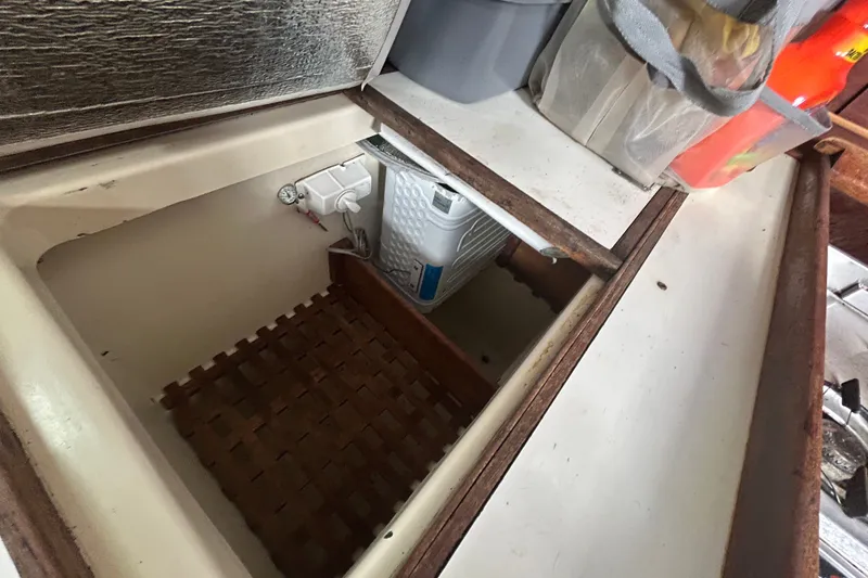 Slide: The Image of Storage compartment in a 1979 Tartan 37 sailboat, featuring a wooden grate and various items. - 37