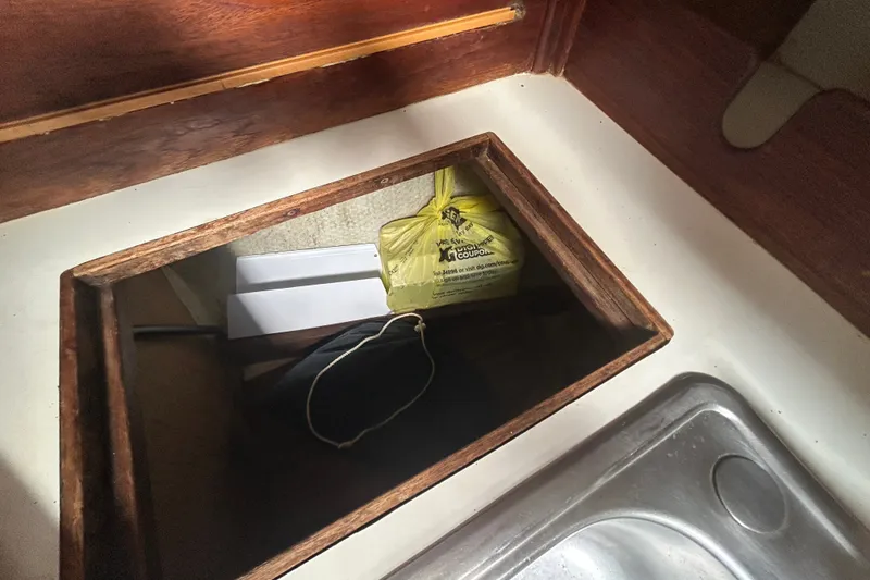 Slide: The Image of Hidden storage compartment in 1979 Tartan 37 sailboat galley with yellow bag and sink nearby. - 35