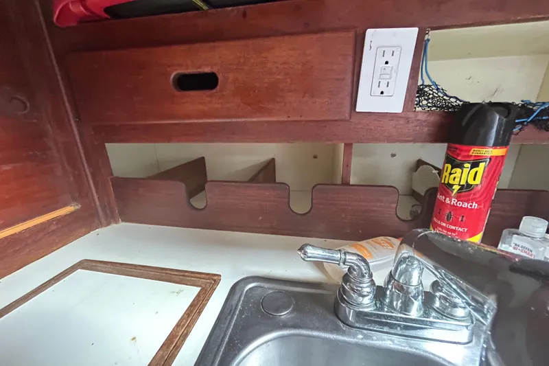 Slide: The Image of 1979 Tartan 37 boat interior with wooden cabinetry, sink, and Raid insect spray. - 36