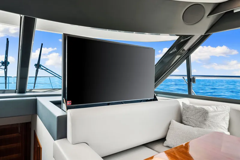 Slide: The Image of 2024 Riviera 4600 Sport Yacht interior with TV, ocean view, and plush seating. - 51