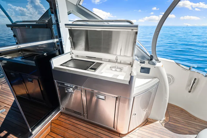 Slide: The Image of Outdoor kitchen on 2024 Riviera 4600 Sport Yacht Platinum Edition, featuring stainless steel appliances. - 30