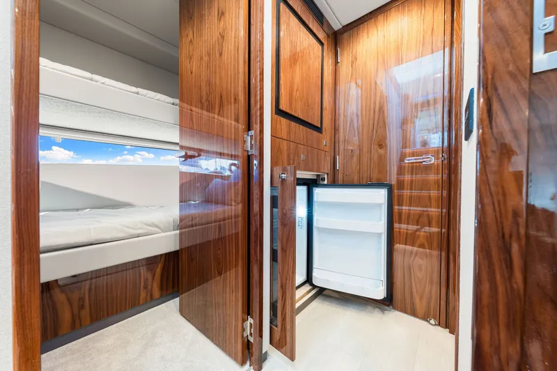 Slide: The Image of Interior of 2024 Riviera 4600 Sport Yacht, featuring wooden cabinetry and a compact refrigerator. - 67